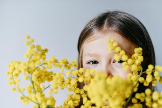 A girl holding mimosa on a white wall background