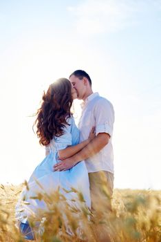 Stylish and modern couple kissing in a wheat field. A young woman hugs her boyfriend and kisses each other. The concept of passion and love.