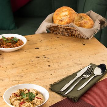 A close up shot of a appetizers near basket of breads on a wooden table