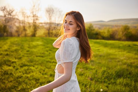 happy woman in a light dress walks through the field during sunset. High quality photo