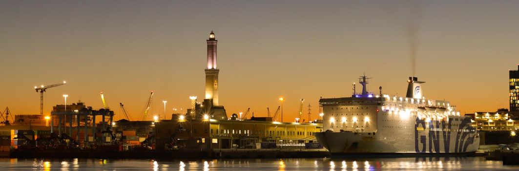 Genova, Italy - July 02, 2022: View of the city and the old harbor (Porto Antico) by night. City lights reflection over the water.