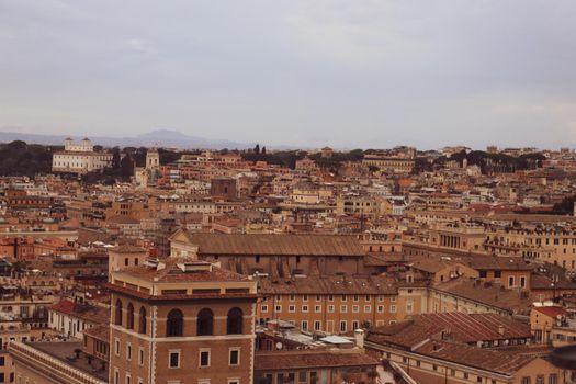 ROME, ITALY - February 05, 2022: Panoramic view around the Colosseum in city of Rome, Italy. Cold and gray sky in the background. Macro photography of the green parks with the old buildings.