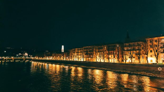 Genova, Italy - July 02, 2022: View of the city and the old harbor (Porto Antico) by night. City lights reflection over the water.