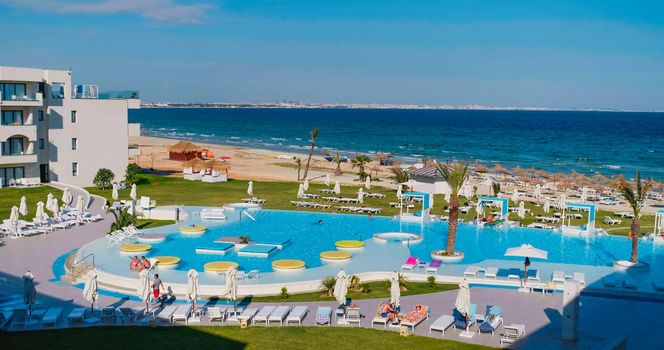 Tunisia, 2022: Beautiful mediterranean sea view from a hotel resort in Tunisia. Beach with palm trees, thatched sun umbrellas. Vacantion destionation in Africa. Tropical landscape.