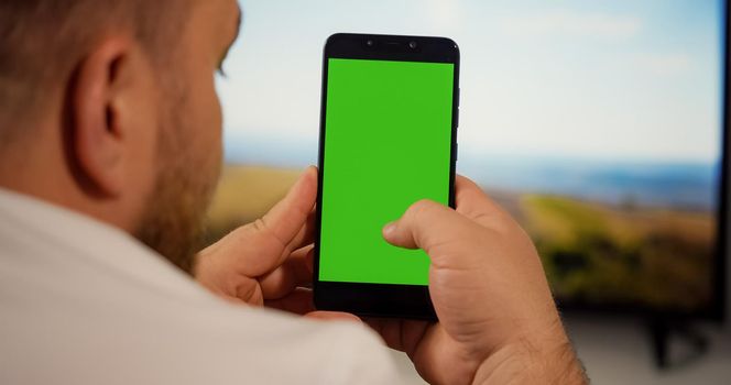 Man Using Smartphone with Green Screen for Copy Space Close up Chroma Key Mockup. Scrolling Gestures. Male watching gadget green screen and touch display.