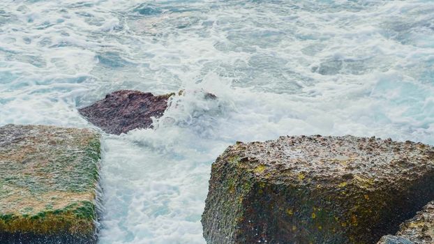 Power of foamy waves breaking over rocks. Stormy Black Sea in cold seasons.