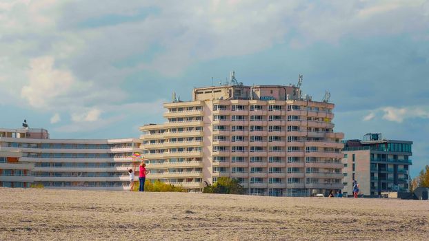 Constanta, Romania , 2021 - Child playing with his grandmother with a kite at the beach. Summer activities at the seaside. Sunny warm day at the sea.