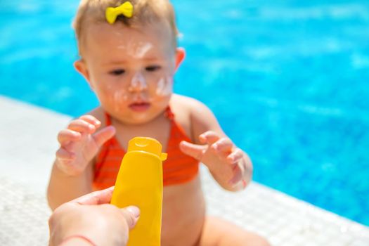 Mother smears sunscreen on the child face. Selective focus. Kid.