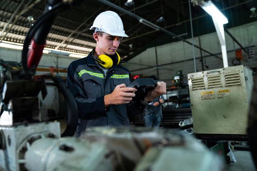 Young factory worker working with adept robotic arm in a workshop . Industry robot programming software for automated manufacturing technology .