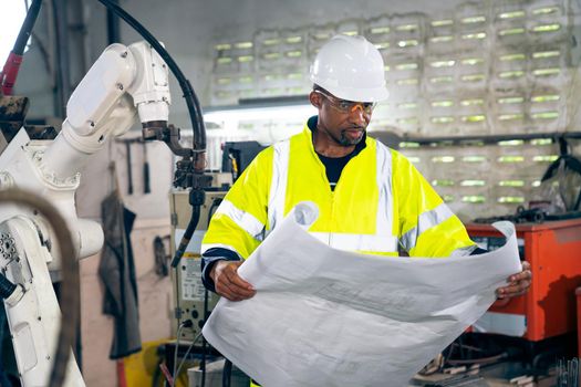 African American factory worker working with adept robotic arm in a workshop . Industry robot programming software for automated manufacturing technology .