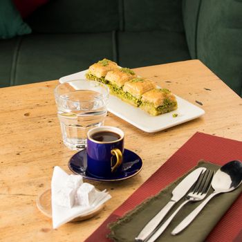 A cup of coffee near glass of water and baklava