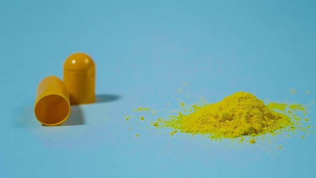 close up opened medicine capsule pill with powder on blue background