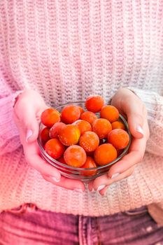 Female hands holding bowl with Frozen Cherry Tomatoes. Vegetable preservation. Harvest. Veganism, vegetarian healthy eating. Fitness diet