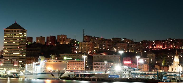 Genova, Italy - July 02, 2022: View of the city and the old harbor (Porto Antico) by night. City lights reflection over the water.