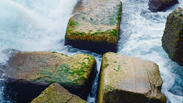 Close up stormy and foamy waves breaking stones