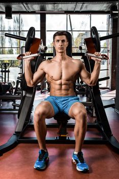 Tense muscles of hands under load. Man doing exercise for biceps in the gym. Work on tell muscles on the simulator. Photos for sporting magazines, posters and websites.