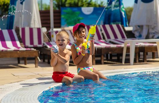 Children play with water pistols in the pool. Selective focus. Water.