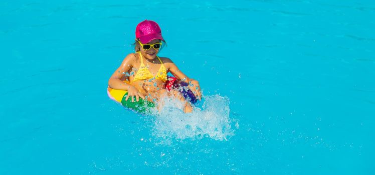 The child swims in the pool in a circle. Selective focus. Kid.