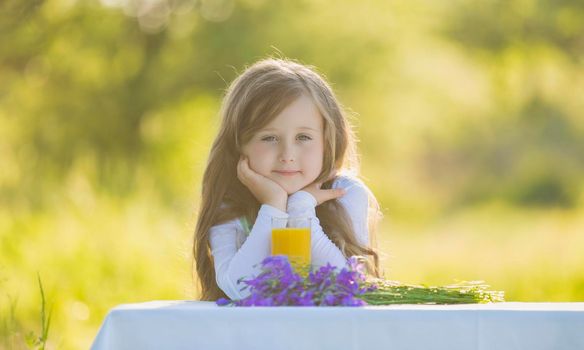 little girl in nature with a glass of orange juice