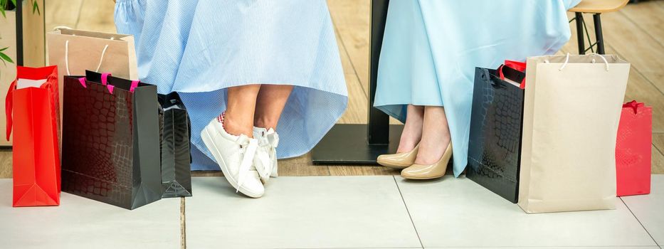 Crop shot of female legs with shopping bags in cafe of the shopping mall