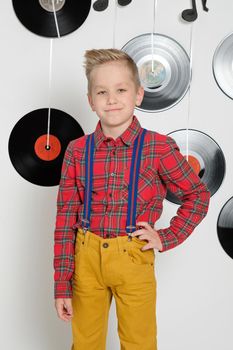 Retro disco 60s, 70s, 80s concept, funny boy wearing red checked shirt, yellow trousers and stylish haircut on a background with music plate
