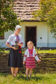 mother and daughter in Ukrainian national costumes near the fence