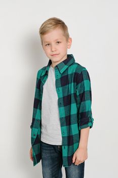 Portrait of cute stylish blond boy kid 7 years old in checked tartan shirt and jeans