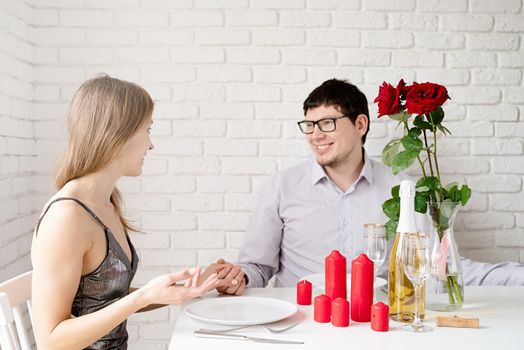 Handsome young man and attractive young woman spending time together, having champagne and candles
