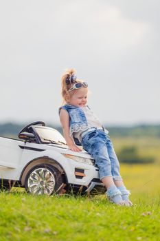 little girl standing near her baby car