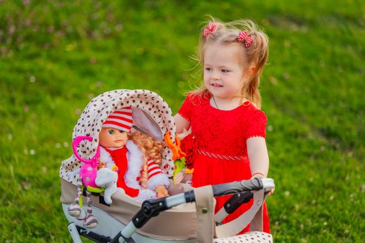 girl plays with her doll who is sitting in a toy stroller