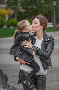 Mom carries her daughter in her arms while walking in the city