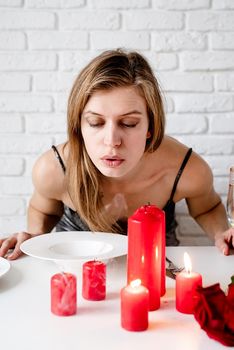 Romantic date, young woman blowing out candle on romantic date table
