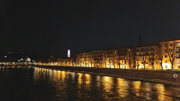 Genova, Italy - July 02, 2022: View of the city and the old harbor (Porto Antico) by night. City lights reflection over the water.