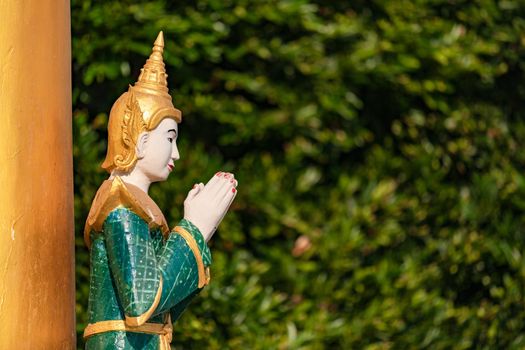 A statue of a Buddha with hands clasped in a temple in Bago, Myanmar