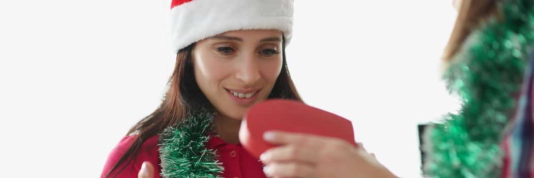 Portrait of woman giving present to best friend in beautiful red box. Festive mood and christmas outfit, ready to celebrate new year. Holiday, gift concept