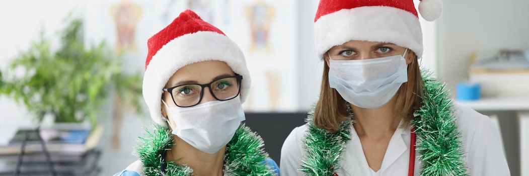 Portrait of medical workers meet new year in hospital with decoration. Nurse and doctor wear santa claus hats on reception. New year, medicine, fun concept