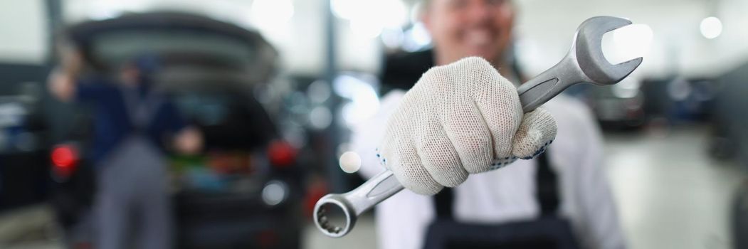 Close-up of car maintenance service worker holding wrench equipment for work. Provide high quality machine service on station. Pit stop, vehicle concept