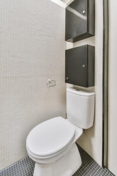 Interior of narrow restroom with toilet with white walls and checkered floor