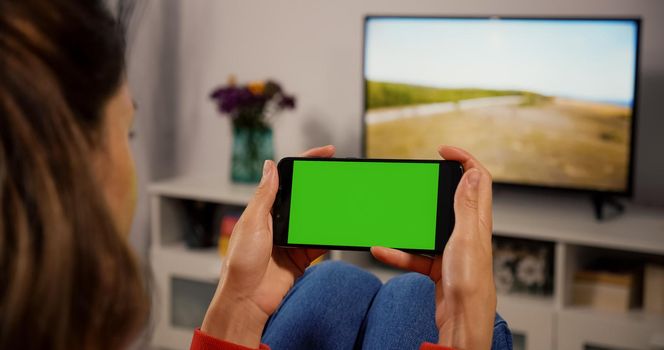 Woman Using Smartphone with Green Screen for Copy Space Close up Chroma Key Mockup. Scrolling Gestures. Girl watcing gadget green screen and touch display.