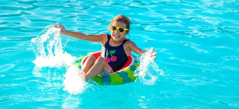 A child in a circle swims in the pool. Selective focus. Kid.