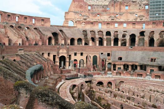 ROME, ITALY - February 05, 2022: Panoramic view around the Colosseum in city of Rome, Italy. Cold and gray sky in the background. Macro photography of the green parks with the old buildings.