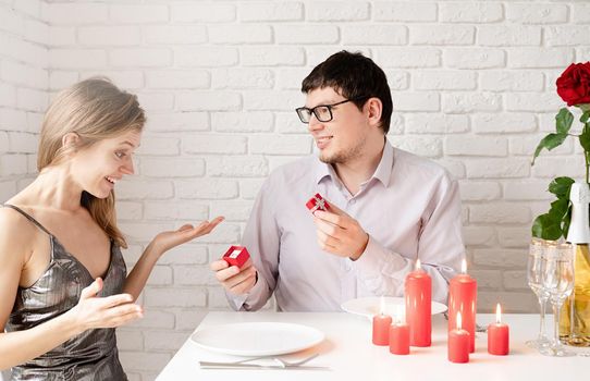 handsome man putting wedding ring on and proposing to his beautiful woman in cafe. Love, anniversary, surprise, people and holidays concept