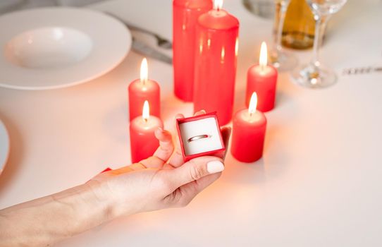 woman hand holding wedding ring in red box