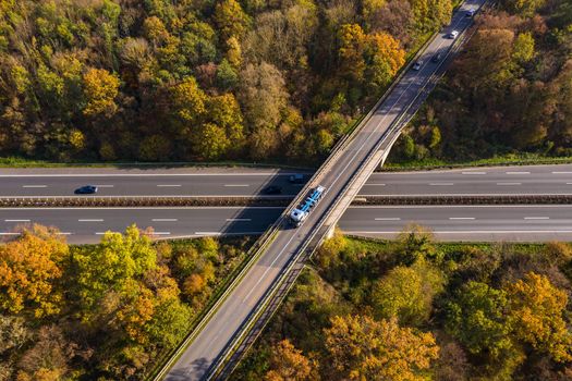 A road crossing through a German mixed forest seen from above in autumn