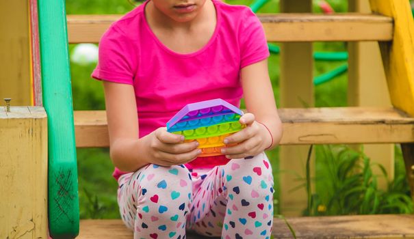 colorful antistress sensory toy fidget push pop it in child hands . Selective focus. nature.