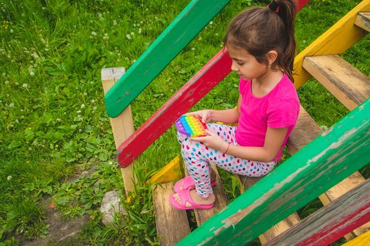 colorful antistress sensory toy fidget push pop it in child hands . Selective focus. nature.