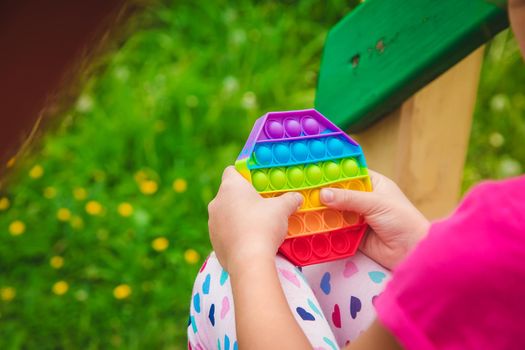 colorful antistress sensory toy fidget push pop it in child hands . Selective focus. nature.