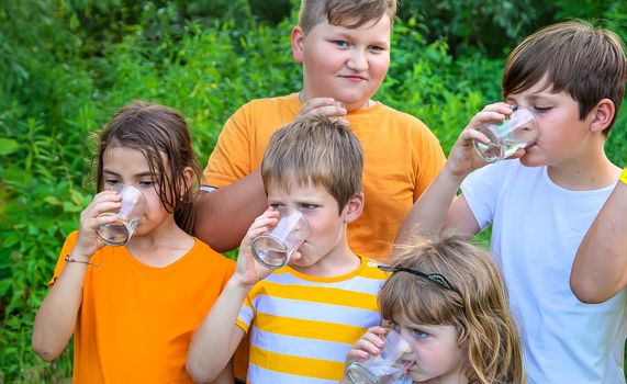 Children drink water outside together. Selective focus. Kids.