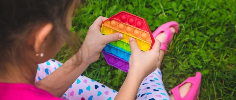 colorful antistress sensory toy fidget push pop it in child hands . Selective focus. nature.