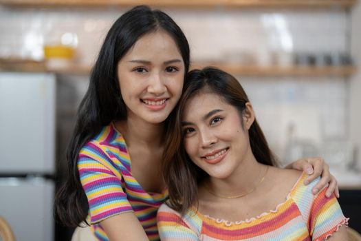 Smiling young lesbian couple standing affectionately together at home.